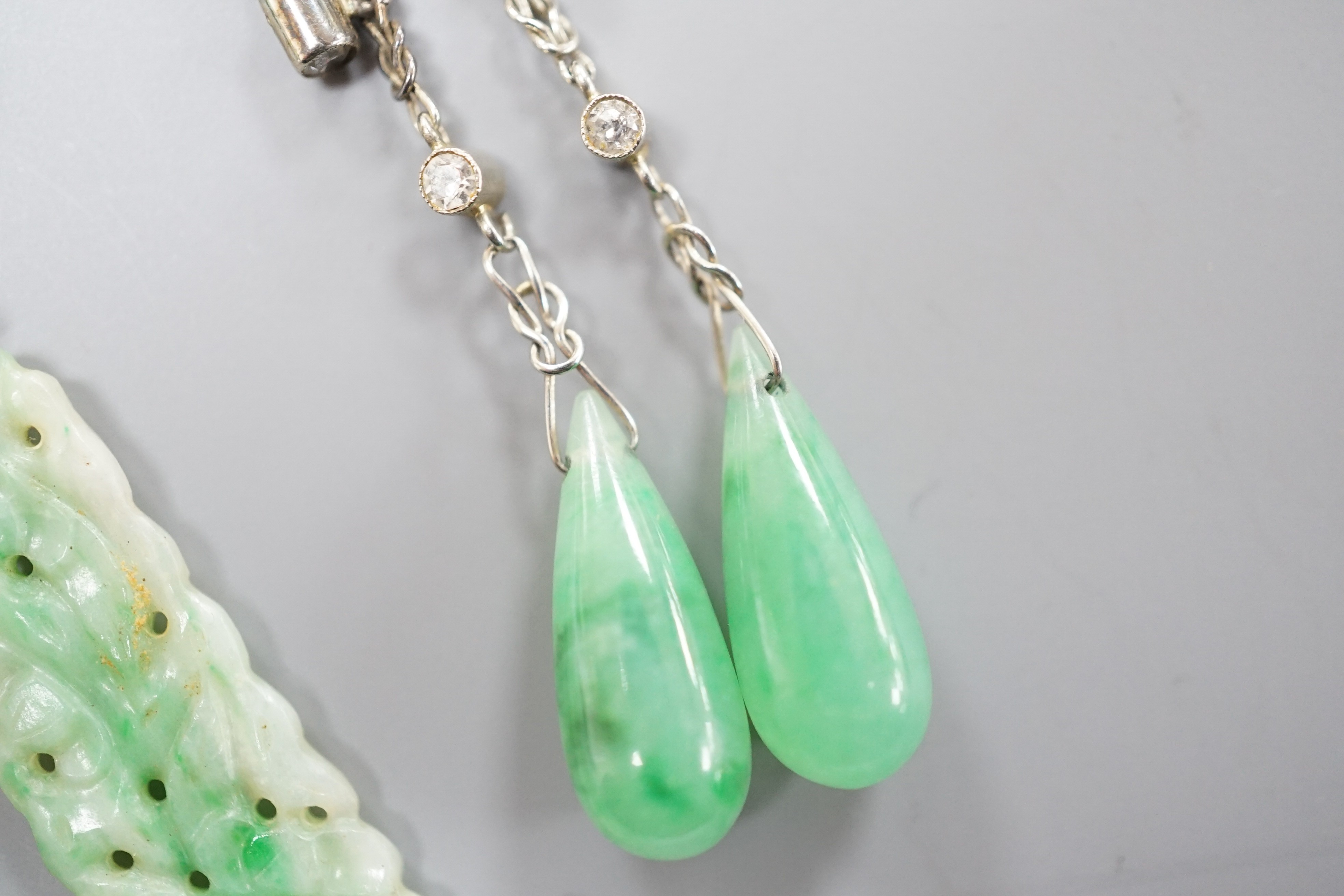 A pair of white metal pair shaped jade and two stone diamond set drop earrings, 37mm and one other pair of carved jade drop earrings, gross weight 8 grams.